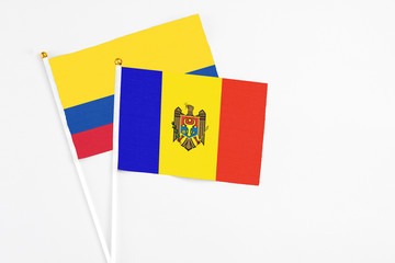 Moldova and Colombia stick flags on white background. High quality fabric, miniature national flag. Peaceful global concept.White floor for copy space.
