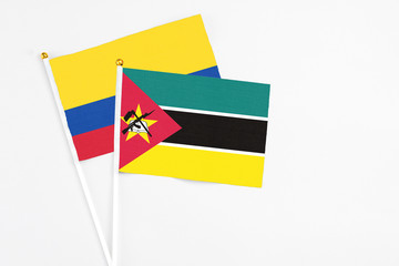Mozambique and Colombia stick flags on white background. High quality fabric, miniature national flag. Peaceful global concept.White floor for copy space.