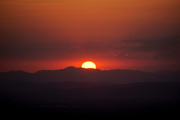 Fototapeta na wymiar the reddish sun behind the mountains
