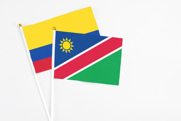 Namibia and Colombia stick flags on white background. High quality fabric, miniature national flag. Peaceful global concept.White floor for copy space.