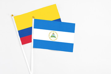 Nicaragua and Colombia stick flags on white background. High quality fabric, miniature national flag. Peaceful global concept.White floor for copy space.