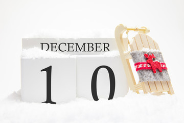Wooden calendar for December, 10 th day of the winter month. The symbols of winter are snow and sleigh. Concept of holidays, vacation and winter fun.