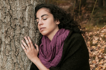 Young woman, dressed in casual clothes, with relaxed attitude, in a forest with autumn colors.