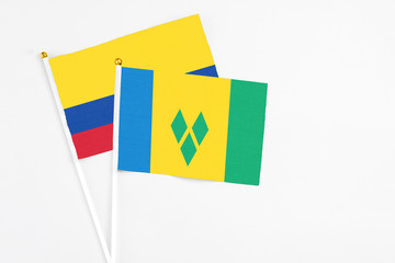 Saint Vincent And The Grenadines and Colombia stick flags on white background. High quality fabric, miniature national flag. Peaceful global concept.White floor for copy space.