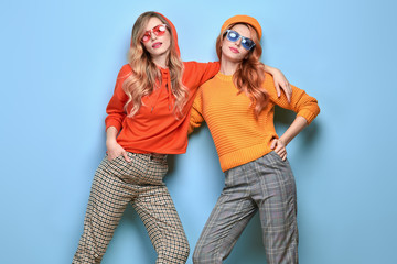 Two easy-going happy hipster Woman smiling, Stylish fashion orange colored outfit. Beautiful Girl...