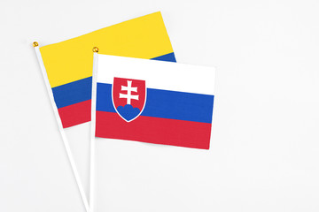 Slovakia and Colombia stick flags on white background. High quality fabric, miniature national flag. Peaceful global concept.White floor for copy space.