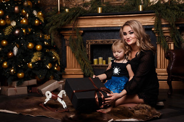 Smiling joyful mom with her daughter near the Christmas tree New Year, Christmas concept are playing