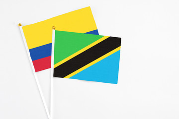 Tanzania and Colombia stick flags on white background. High quality fabric, miniature national flag. Peaceful global concept.White floor for copy space.