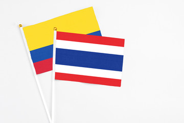 Thailand and Colombia stick flags on white background. High quality fabric, miniature national flag. Peaceful global concept.White floor for copy space.