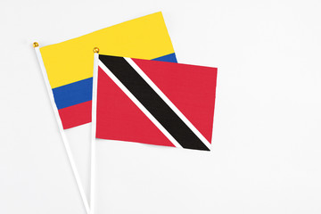 Trinidad And Tobago and Colombia stick flags on white background. High quality fabric, miniature national flag. Peaceful global concept.White floor for copy space.