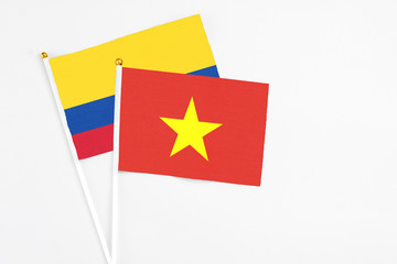 Vietnam and Colombia stick flags on white background. High quality fabric, miniature national flag. Peaceful global concept.White floor for copy space.