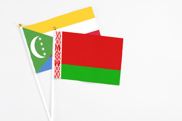 Belarus and Comoros stick flags on white background. High quality fabric, miniature national flag. Peaceful global concept.White floor for copy space.