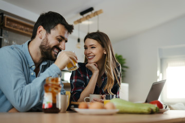 Young smiling couple communicating during breakfast time in the kitchen