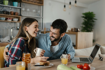Young cheerful couple having fun during breakfast time in the kitchen