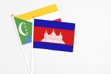 Cambodia and Comoros stick flags on white background. High quality fabric, miniature national flag. Peaceful global concept.White floor for copy space.