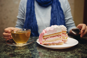 Beautiful young woman eating sweet food - pink cake and tea