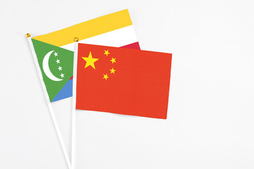 China and Comoros stick flags on white background. High quality fabric, miniature national flag. Peaceful global concept.White floor for copy space.