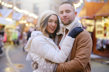 Beautiful romantic couple enjoy their Christmas day on traditional festive market.