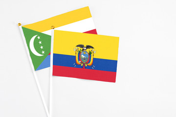 Ecuador and Comoros stick flags on white background. High quality fabric, miniature national flag. Peaceful global concept.White floor for copy space.