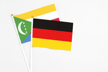 Germany and Comoros stick flags on white background. High quality fabric, miniature national flag. Peaceful global concept.White floor for copy space.