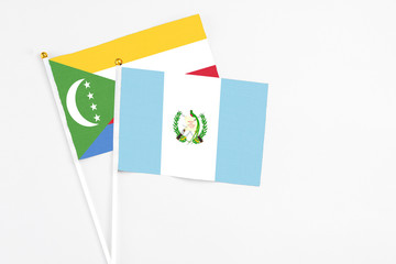 Guatemala and Comoros stick flags on white background. High quality fabric, miniature national flag. Peaceful global concept.White floor for copy space.