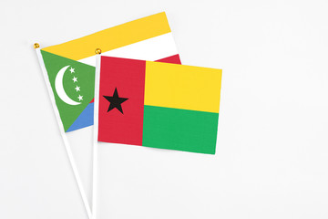 Guinea Bissau and Comoros stick flags on white background. High quality fabric, miniature national flag. Peaceful global concept.White floor for copy space.