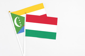 Hungary and Comoros stick flags on white background. High quality fabric, miniature national flag. Peaceful global concept.White floor for copy space.