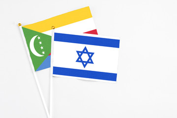 Israel and Comoros stick flags on white background. High quality fabric, miniature national flag. Peaceful global concept.White floor for copy space.