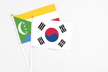 South Korea and Comoros stick flags on white background. High quality fabric, miniature national flag. Peaceful global concept.White floor for copy space.