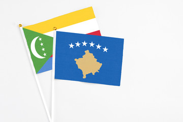 Kosovo and Comoros stick flags on white background. High quality fabric, miniature national flag. Peaceful global concept.White floor for copy space.