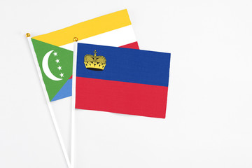 Liechtenstein and Comoros stick flags on white background. High quality fabric, miniature national flag. Peaceful global concept.White floor for copy space.