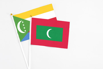 Maldives and Comoros stick flags on white background. High quality fabric, miniature national flag. Peaceful global concept.White floor for copy space.