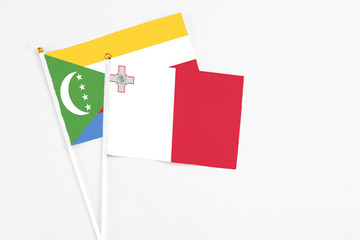 Malta and Comoros stick flags on white background. High quality fabric, miniature national flag....