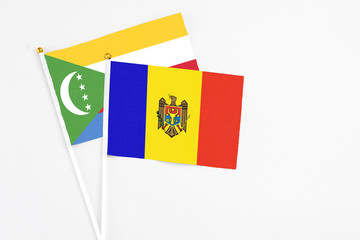 Moldova and Comoros stick flags on white background. High quality fabric, miniature national flag. Peaceful global concept.White floor for copy space.
