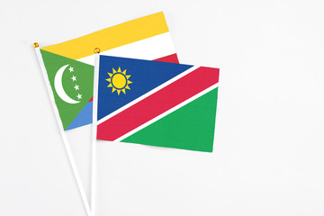 Namibia and Comoros stick flags on white background. High quality fabric, miniature national flag. Peaceful global concept.White floor for copy space.