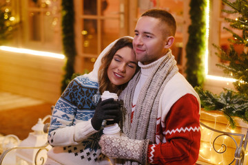 Charming couple feels happy while enjoying Christmas Eve on decorated street.