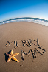 Wide angle view of Merry X-mas message written in the sand decorated with a natural starfish