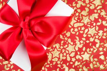 Simple white gift box with shiny red satin bow on abstract background of interconnected stars