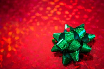 Christmas present wrapped in sparkling red holiday paper topped by a shiny green bow