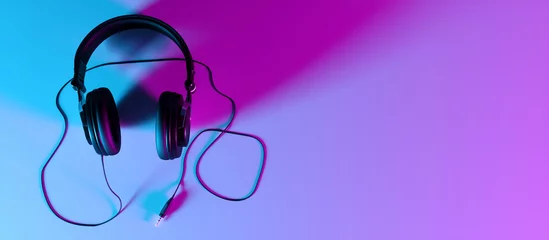 Zelfklevend Fotobehang headphones on a black background close-up in neon light © zeleniy9