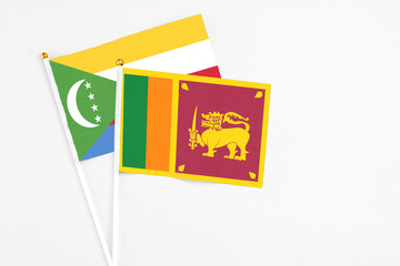 Sri Lanka and Comoros stick flags on white background. High quality fabric, miniature national flag. Peaceful global concept.White floor for copy space.