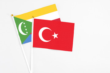 Turkey and Comoros stick flags on white background. High quality fabric, miniature national flag. Peaceful global concept.White floor for copy space.