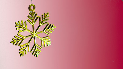 One golden plastic snowflake decoration on a red background.