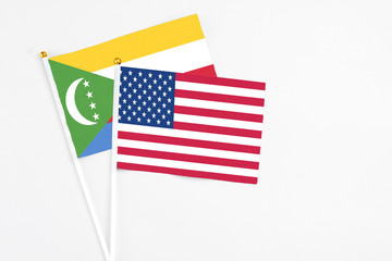 United States and Comoros stick flags on white background. High quality fabric, miniature national flag. Peaceful global concept.White floor for copy space.
