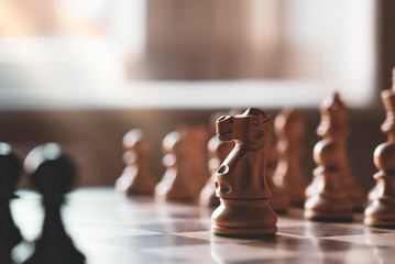 Selective focus of wood knight chess on board game with blurry background, Business leader and confrontation solve problems concept, Chess horse on board with copy space