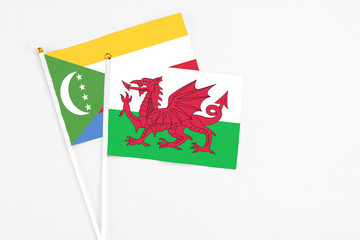 Wales and Comoros stick flags on white background. High quality fabric, miniature national flag. Peaceful global concept.White floor for copy space.