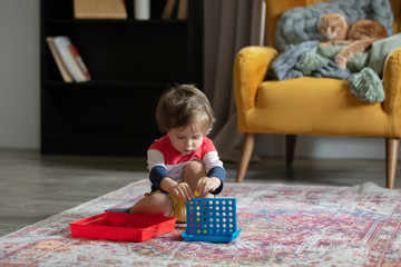 Little toddler boy play on floor and cat on background
