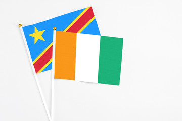 Cote D'Ivoire and Congo stick flags on white background. High quality fabric, miniature national flag. Peaceful global concept.White floor for copy space.