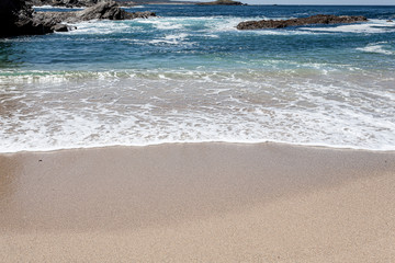 Onda com a sua espuma branca na areia da praia.