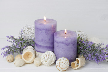 Fototapeta na wymiar spa concept of purple burning candles decorated in natural dried potpourri, lavender, dried floral on white wooden rustic background